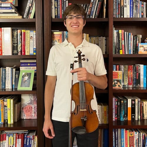 music theory teacher and violin teacher in Oakville Nicolas Wojtarowicz standing with violin in hand in front of bookcase